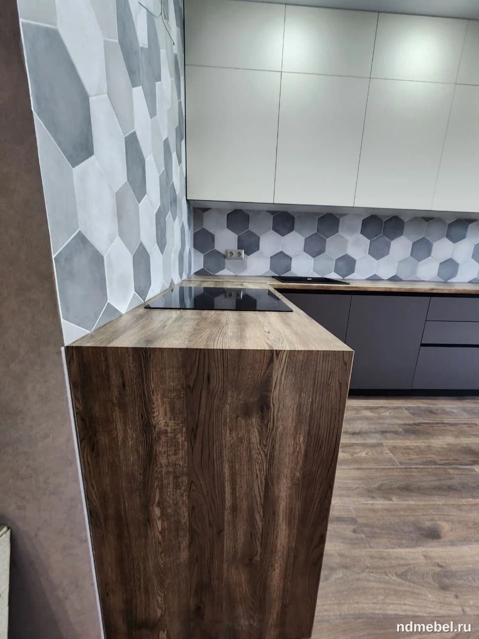 Современный кухонный гарнитур с фасадами из темного дерева (или его имитации) внизу и белыми матовыми шкафами вверху, дополненный столешницей под дерево и шестиугольной плиткой в отделке.